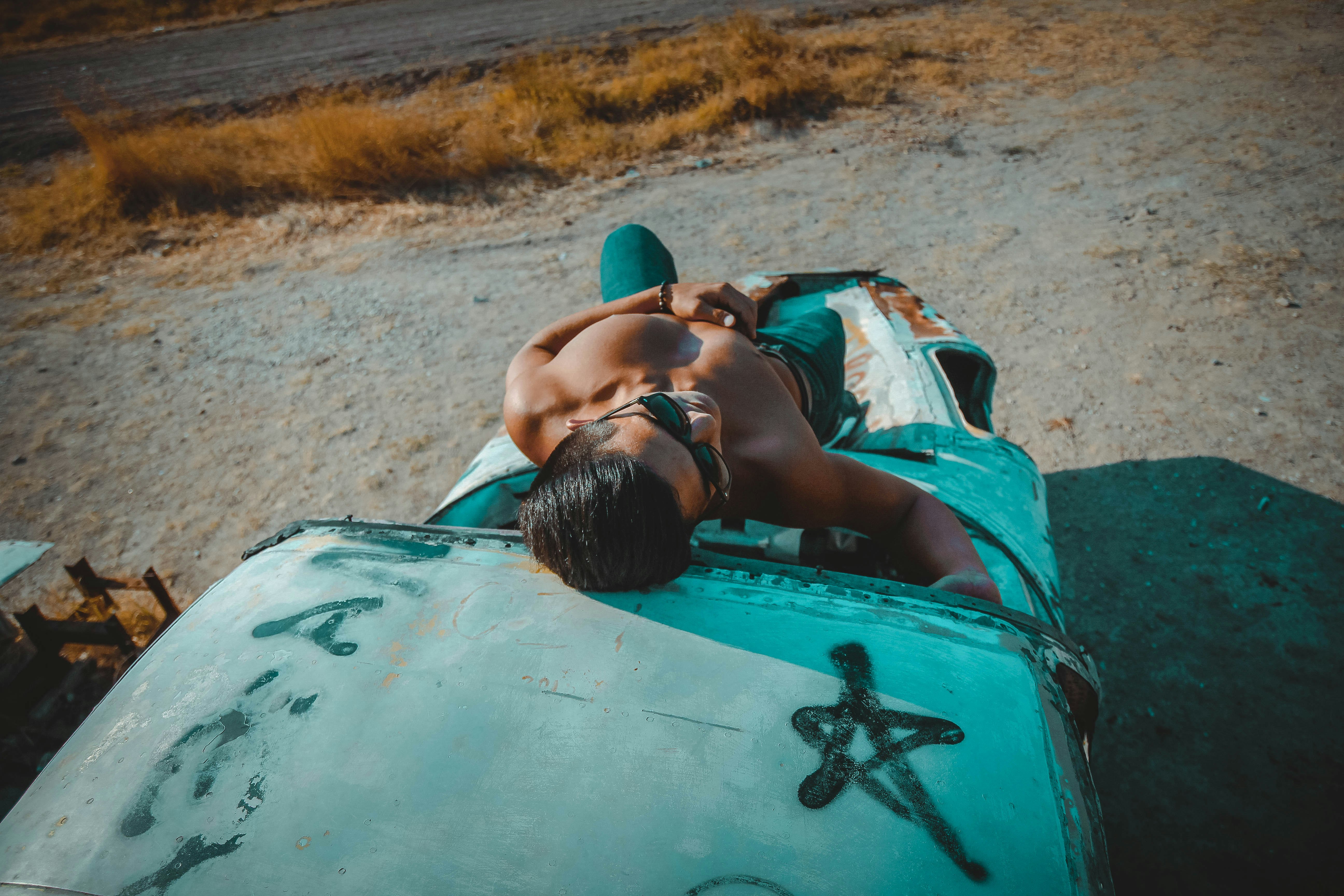 topless man lying on vehicle hood